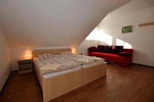 チェルニー・ドゥールにあるChalupa pod vrškemのベッドルーム1室(ベッド1台、赤いソファ付)