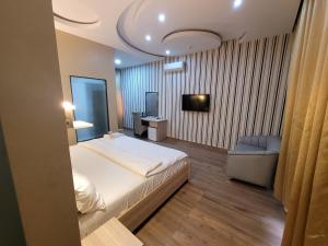 a bedroom with a bed and a chair and a television at The Charis Hotel & Suites in Port Harcourt