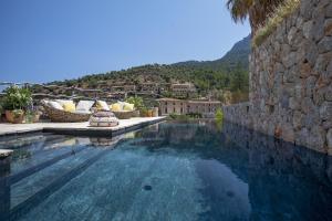 une grande piscine à côté d'un mur en pierre dans l'établissement Casa Berne - Deia, à Deià