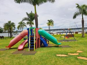 een speeltuin met een glijbaan in een park met palmbomen bij Life Resort Flat - Torre F - Beira do lago in Brasilia