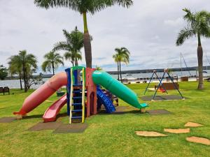 a playground with a slide in a park with palm trees at Life Resort Flat - Torre F - Beira do lago in Brasília
