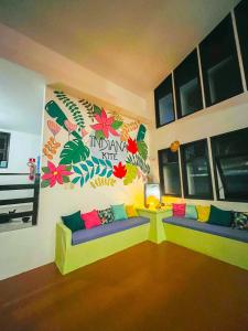 a living room with two couches and flowers on the wall at Indiana Kite school and Hostel in Cumbuco