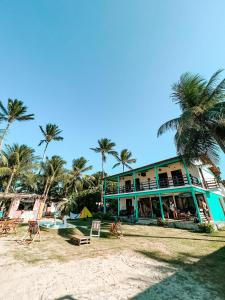 um edifício azul na praia com palmeiras em Indiana Kite school and Hostel em Cumbuco
