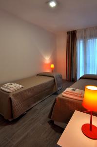 Habitación de hotel con 2 camas y mesa con lámpara en BB Hotels Aparthotel Arcimboldi, en Milán