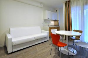 a living room with a white couch and a table at BB Hotels Aparthotel Arcimboldi in Milan +21 photos