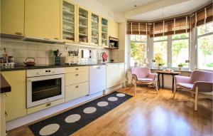 a kitchen with yellow cabinets and a table and chairs at Awesome Home In Limhamn With House Sea View in Malmö