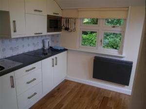a kitchen with white cabinets and a flat screen tv at Shieling Beag in Banchory
