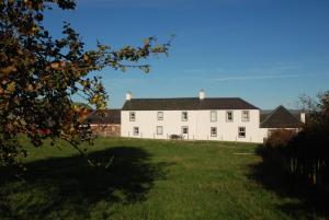 a large white house with a large grassy yard at Pant Farmhouse in Ayr