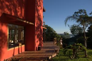 a woman standing on a porch of a red house at El Soberbio Lodge in El Soberbio