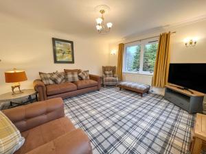 a living room with a couch and a tv at Creag Dhubh Cottage in Newtonmore