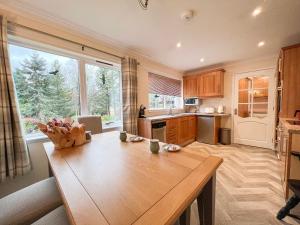 a kitchen with a wooden table and a large window at Creag Dhubh Cottage in Newtonmore