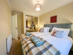Un dormitorio con dos camas y un espejo. en Creag Dhubh Cottage, en Newtonmore