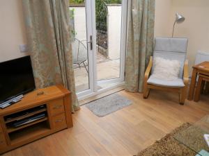 a living room with a television and a chair at Laurieknowe Coach House in Dumfries