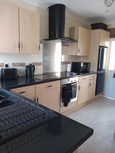 a kitchen with wooden cabinets and a stove top oven at Laurieknowe Coach House in Dumfries