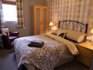 a bedroom with a bed with a pile of towels on it at Laurieknowe Coach House in Dumfries