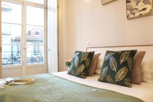 um quarto com uma cama com almofadas e uma janela em Aliados Sunny Flat no Porto