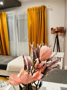 a vase of pink flowers on a table in a bedroom at Confort View Apartment Iași - 3 rooms-Like Home in Iaşi