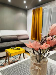 a living room with a couch and a vase with flowers at Confort View Apartment Iași - 3 rooms-Like Home in Iaşi