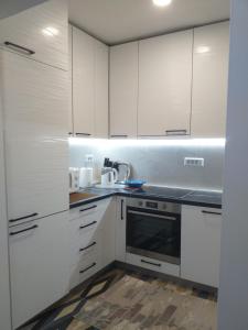 - une cuisine blanche avec des placards blancs et un évier dans l'établissement Trosoban apartman Sarajevo, Ilidza centar, à Sarajevo