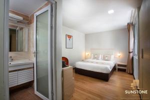 a bedroom with a bed and a bathroom with a sink at Sunstone Hotel in George Town