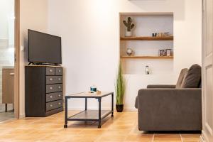 - un salon avec une télévision, un canapé et une table dans l'établissement Studio Ingres au coeur historique de Montauban, à Montauban