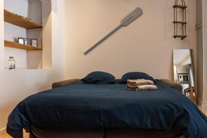 - une chambre avec un lit bleu et des serviettes dans l'établissement Studio Ingres au coeur historique de Montauban, à Montauban
