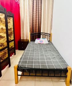 Cama pequeña en habitación con pared roja en JJR Short stay-sharing en Abu Dabi