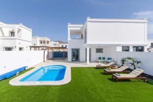 a backyard with a swimming pool and green grass at Casa Princesa Gara in Yaiza