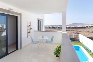 balcón con mesa y sillas y piscina en Casa Princesa Gara, en Yaiza