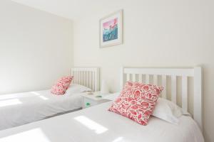 two beds with pink pillows in a white room at Polly's Folly in Swanage