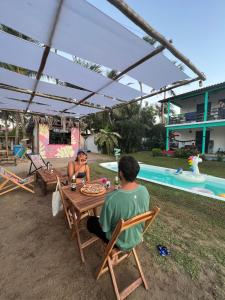 Ein Mann und eine Frau sitzen an einem Tisch in der Nähe eines Pools in der Unterkunft Indiana Kite school and Hostel in Cumbuco