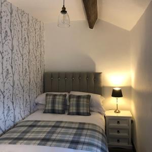 a bedroom with a bed and a night stand with a lamp at Mistletoe Cottage in Foulridge