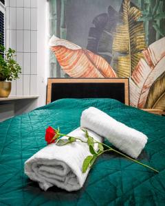 a bed with a towel and a rose on it at Jacuzzi & Bike Apartment, Krakow in Krakow