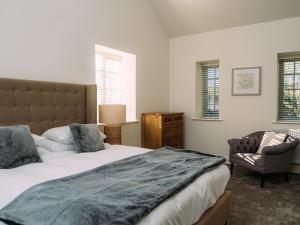 a bedroom with a bed and a chair and windows at The Groomsmen in Clitheroe