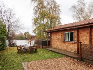 a wooden cabin with a table and a bench at Avocet Lodge in Lincoln