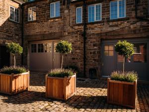 four wooden planters with plants in front of a building at The Gardener in Clitheroe