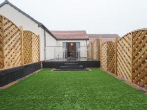 a garden with a fence and grass at Honeysuckle in Hull