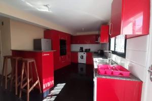 a red kitchen with red cabinets and a sink at villa luxueuse et meublée plus de 280 m² in Antananarivo