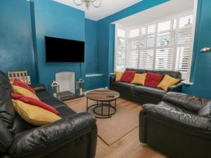 a living room with two leather couches and a table at Glanffrwd - Nefyn in Pwllheli