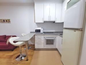 - une cuisine blanche avec une table et un réfrigérateur dans l'établissement Castrelos, Vigo, diseño, à Vigo