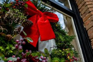 a christmas wreath with a red bow on a window at Boutique Hotel De Castillion - Small elegant family hotel in Bruges