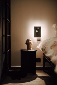 a nightstand with a bust on it next to a bed at Comme chez Lore - villa 2pers - piscine chauffée in Namur