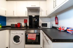 a kitchen with a washing machine and a microwave at Beside The Seaside - By My Getaways in Brighton & Hove