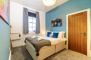 a bedroom with a bed with blue walls and a door at Beside The Seaside - By My Getaways in Brighton & Hove