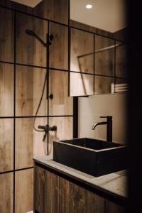 y baño con lavabo negro y ducha. en Comme chez Lore - villa 2pers - piscine chauffée, en Namur