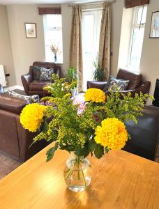 a vase with yellow flowers on a wooden table at Luxurious two-bedroom apartment in the centre of Peterborough in Peterborough