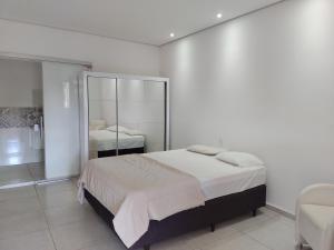 a white bedroom with a bed and a mirror at Pousada Viva Vida in Águas de Lindóia +48 photos