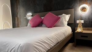 um quarto com uma cama branca e almofadas cor-de-rosa em Patriziella 4 Rooms em Sorrento