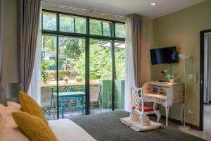 a bedroom with a bed and a desk and a window at Snapper House in Khao Lak