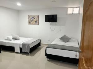 two beds in a room with a tv on the wall at Hotel Dorado San Luis in San Luis